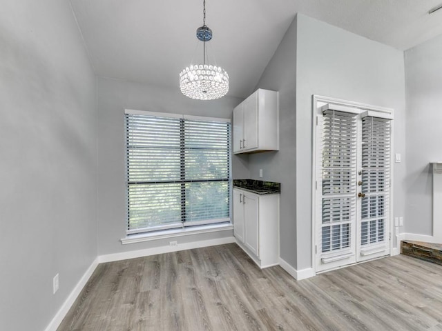 unfurnished dining area featuring light hardwood / wood-style flooring and a notable chandelier