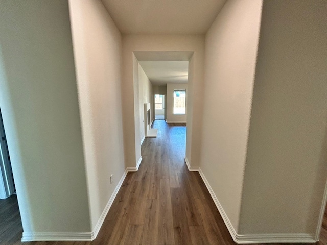 hall featuring baseboards and dark wood-type flooring