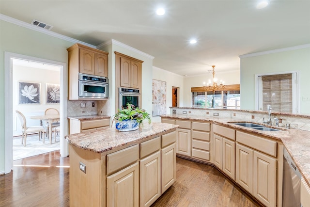 kitchen with light brown cabinetry, sink, a kitchen island, pendant lighting, and stainless steel appliances