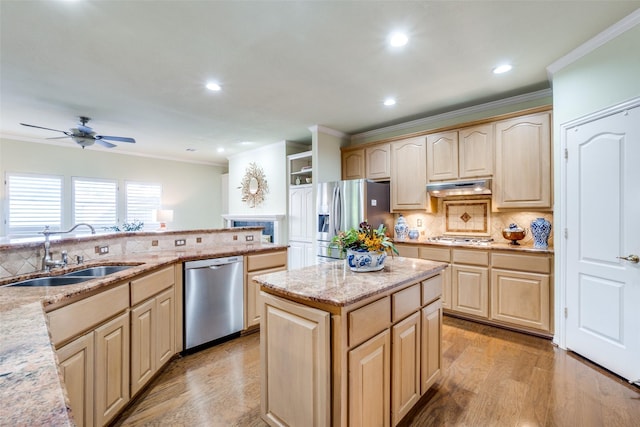 kitchen featuring sink, appliances with stainless steel finishes, light brown cabinets, a kitchen island, and light wood-type flooring