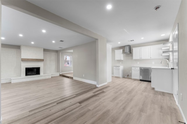 unfurnished living room featuring light hardwood / wood-style floors, sink, and a fireplace