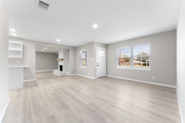 unfurnished living room with light wood-type flooring and a large fireplace