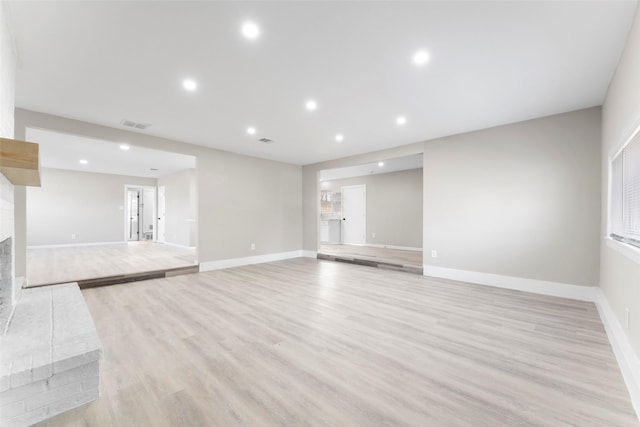 unfurnished living room with a brick fireplace and light hardwood / wood-style floors