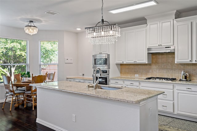 kitchen featuring stainless steel appliances, an island with sink, and white cabinets