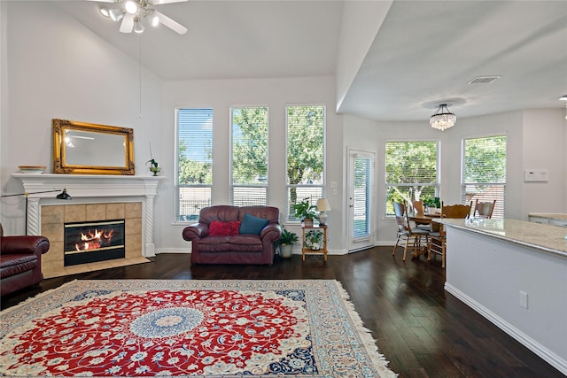 living room with ceiling fan, a healthy amount of sunlight, dark hardwood / wood-style flooring, and a tiled fireplace