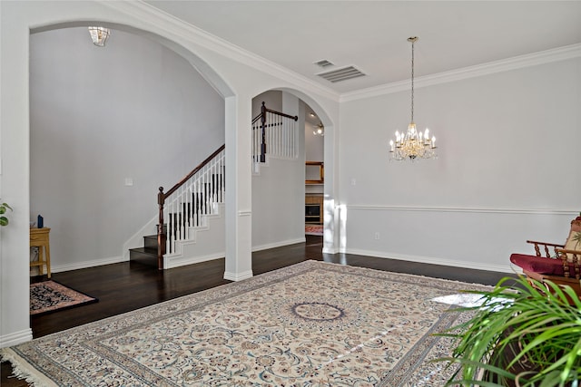 entrance foyer featuring crown molding, dark wood-type flooring, and a notable chandelier