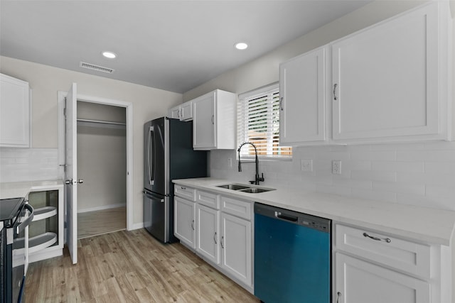 kitchen with white cabinets, black dishwasher, light hardwood / wood-style floors, sink, and stainless steel refrigerator