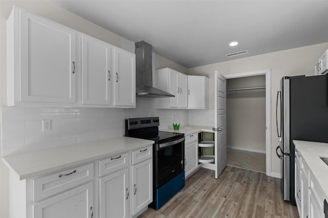 kitchen with appliances with stainless steel finishes, white cabinetry, tasteful backsplash, and wall chimney range hood