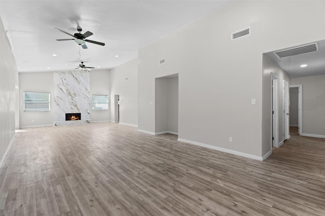 unfurnished living room with a premium fireplace, light hardwood / wood-style flooring, and ceiling fan