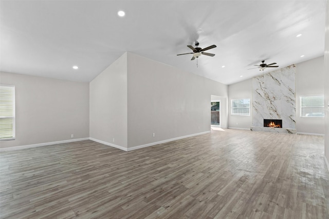 unfurnished living room with ceiling fan, lofted ceiling, a fireplace, and hardwood / wood-style flooring