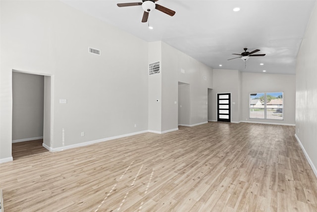 unfurnished living room featuring light wood-type flooring, ceiling fan, and a high ceiling