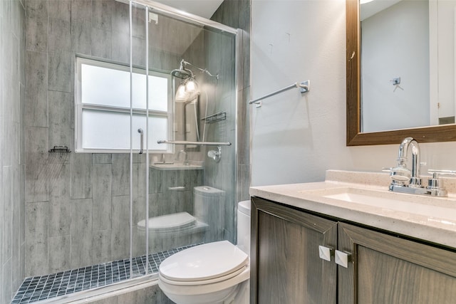 bathroom featuring toilet, a shower with door, and vanity