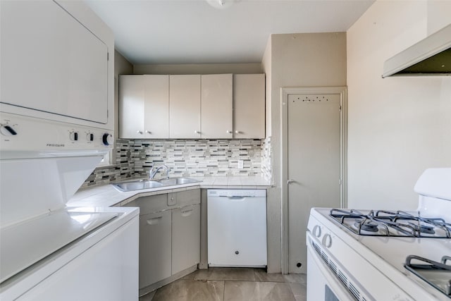 kitchen featuring white appliances, white cabinetry, sink, stacked washer and clothes dryer, and range hood