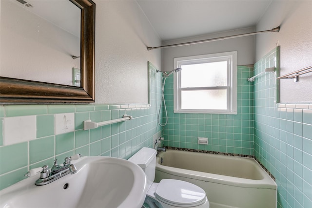 full bathroom with toilet, tile walls, tiled shower / bath, and sink