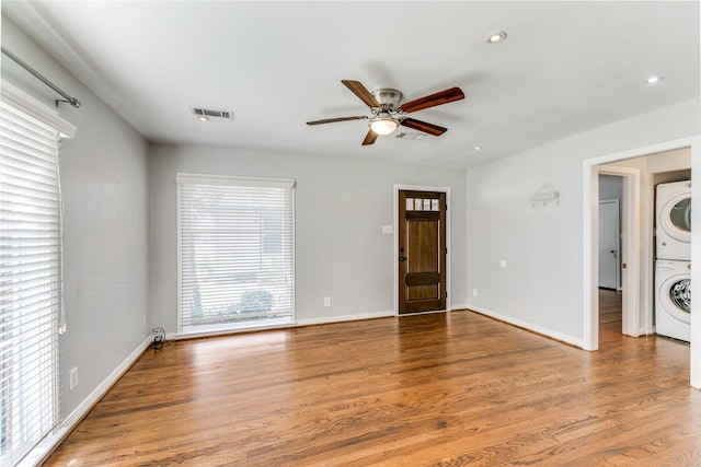 interior space with ceiling fan, stacked washer and clothes dryer, and hardwood / wood-style floors