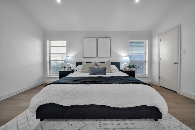 bedroom featuring lofted ceiling, hardwood / wood-style flooring, and multiple windows