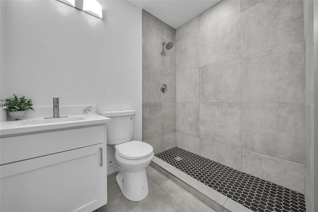 bathroom featuring toilet, vanity, and a tile shower