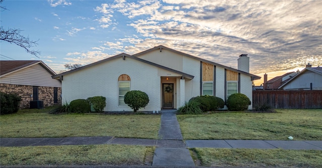 view of front of property with a yard and central AC