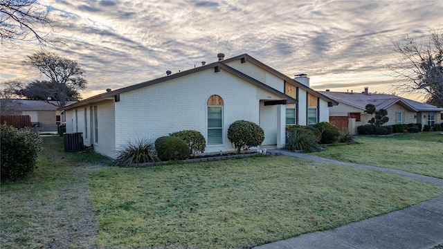 property exterior at dusk featuring cooling unit and a lawn