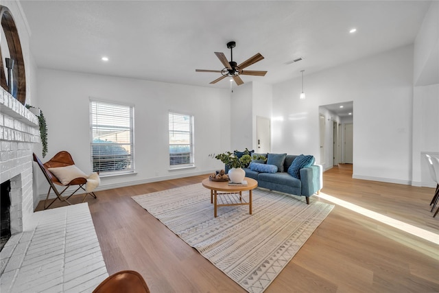 living room with ceiling fan, light hardwood / wood-style flooring, and a fireplace