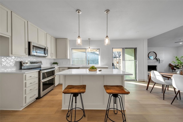 kitchen with backsplash, a center island, white cabinetry, appliances with stainless steel finishes, and a breakfast bar area