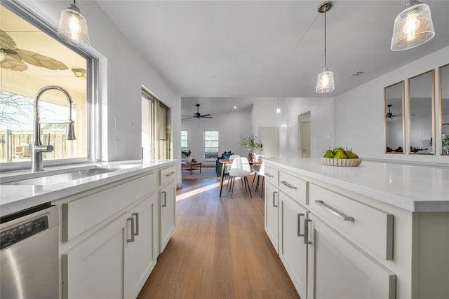 kitchen with stainless steel dishwasher, sink, hanging light fixtures, and white cabinetry