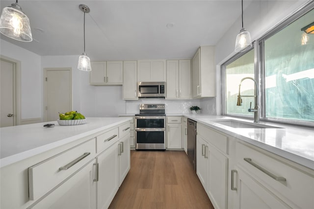 kitchen with decorative light fixtures, sink, and stainless steel appliances