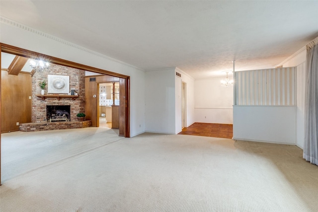 unfurnished living room with crown molding, a fireplace, carpet flooring, and a notable chandelier