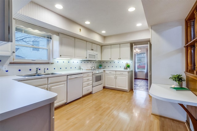 kitchen featuring sink, white appliances, plenty of natural light, light hardwood / wood-style floors, and white cabinets