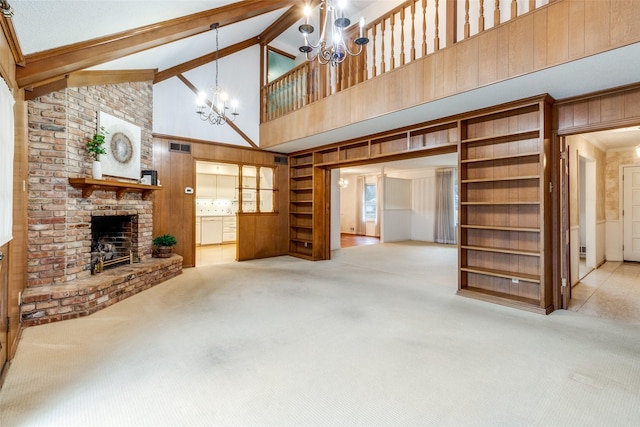 unfurnished living room featuring light colored carpet, beam ceiling, a chandelier, and a fireplace