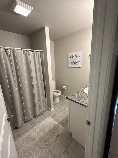 bathroom featuring tile patterned floors, toilet, vanity, and a textured ceiling