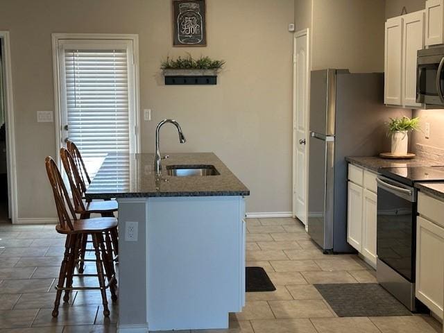 kitchen featuring white cabinets, stainless steel appliances, an island with sink, sink, and a kitchen breakfast bar