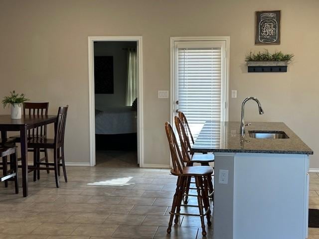 kitchen featuring kitchen peninsula, a kitchen bar, sink, and dark stone countertops