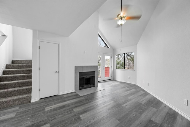 unfurnished living room featuring ceiling fan, dark wood-type flooring, a fireplace, french doors, and high vaulted ceiling