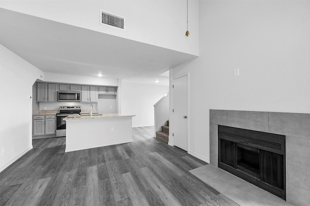 kitchen with gray cabinets, stainless steel appliances, pendant lighting, light stone counters, and sink