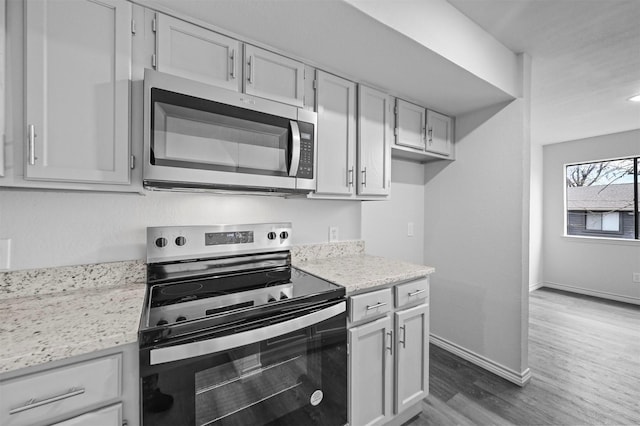 kitchen with stainless steel appliances, dark hardwood / wood-style flooring, and light stone countertops