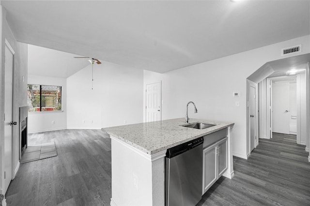 kitchen featuring a center island with sink, lofted ceiling, light stone countertops, stainless steel dishwasher, and sink