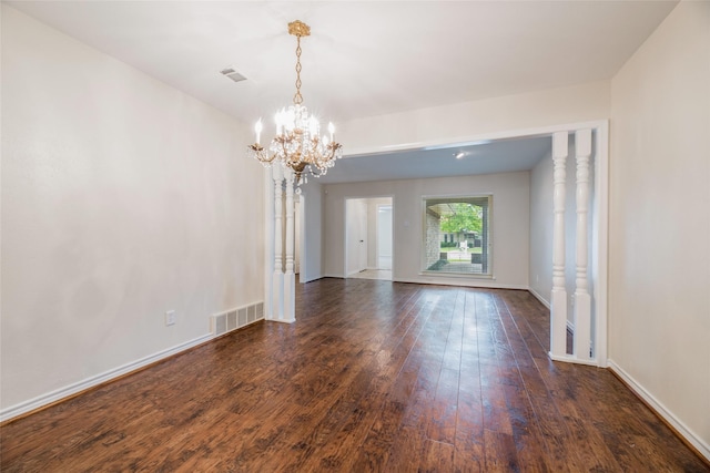 unfurnished room featuring dark wood-type flooring and an inviting chandelier