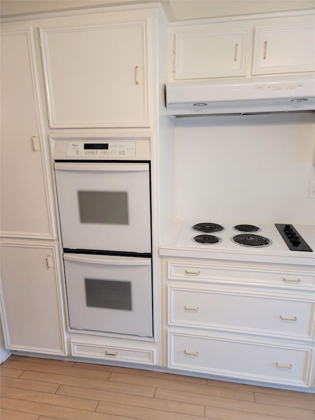 kitchen with light wood-type flooring, white cabinets, and white appliances