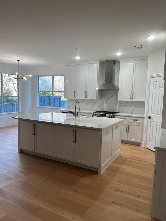 kitchen featuring light hardwood / wood-style floors, sink, wall chimney range hood, and white cabinets