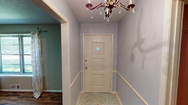 entryway featuring a textured ceiling and a notable chandelier