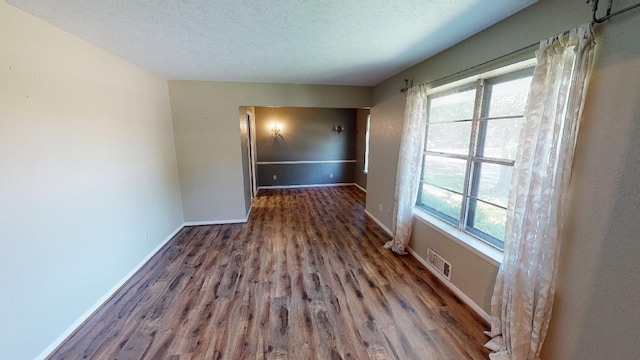 unfurnished room with a textured ceiling, dark wood-type flooring, and a wealth of natural light