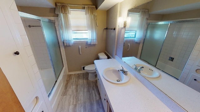 full bathroom with toilet, vanity, and bath / shower combo with glass door