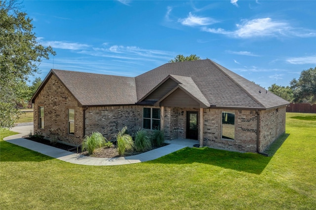 single story home featuring brick siding, roof with shingles, and a front yard