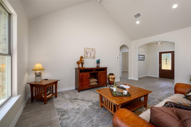 living room featuring arched walkways, a wealth of natural light, wood finished floors, and visible vents