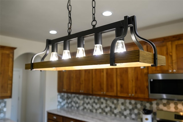 interior details featuring brown cabinets, stainless steel microwave, light countertops, and recessed lighting