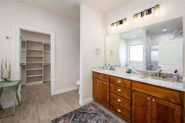 full bath featuring a walk in shower, a sink, wood finished floors, a spacious closet, and double vanity