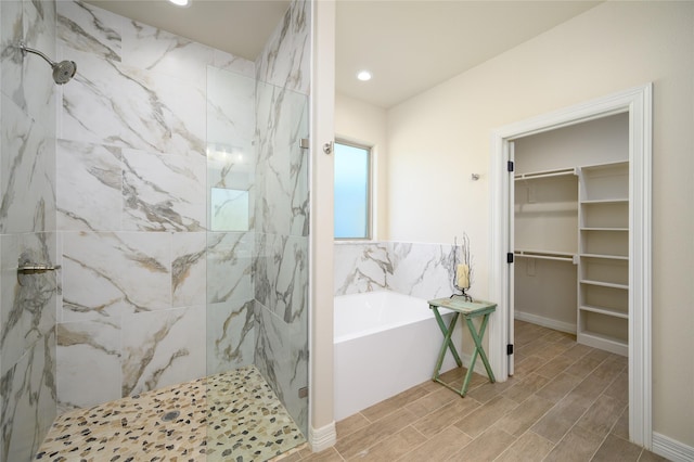 bathroom featuring recessed lighting, a spacious closet, a marble finish shower, and a bath