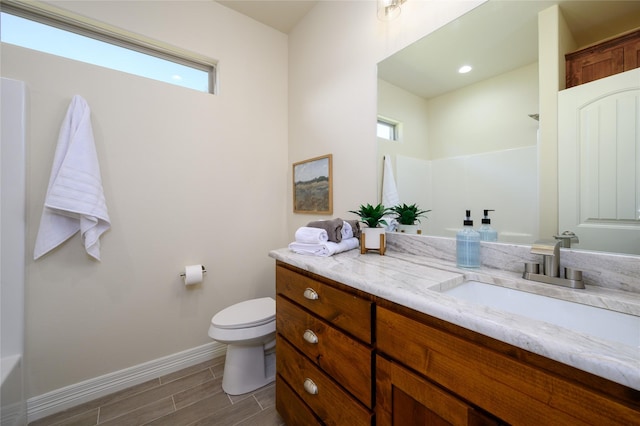 full bath featuring toilet, wood tiled floor, baseboards, and vanity