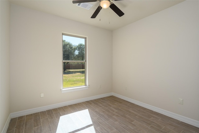 unfurnished room featuring plenty of natural light, wood finished floors, visible vents, and baseboards